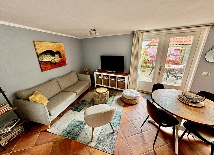 Cozy living room in vacation home Texel A, De Koog, with comfortable seating area and garden view.