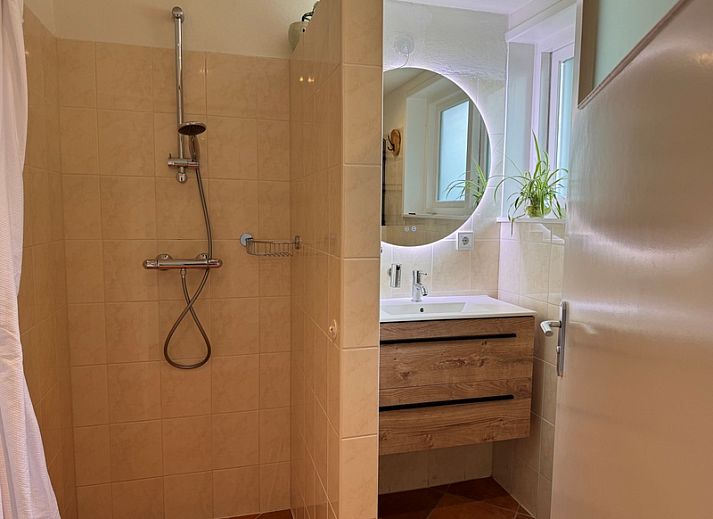 Cozy living room in vacation home Texel A, De Koog, with comfortable seating area and garden view.