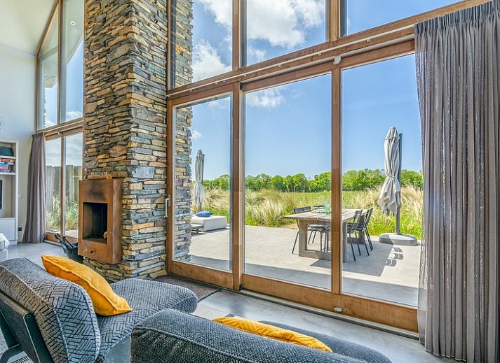 Cozy living room in Villa 193, De Koog, Texel, with fireplace and views of the natural surroundings.
