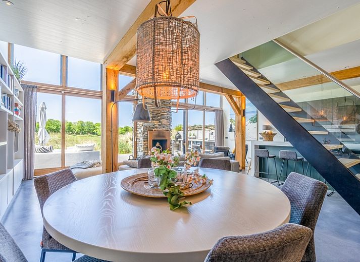 Cozy living room in Villa 193, De Koog, Texel, with fireplace and views of the natural surroundings.