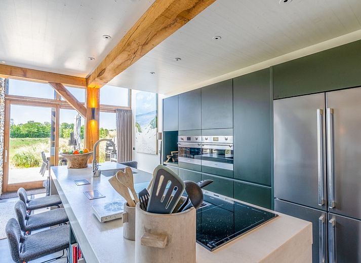 Cozy living room in Villa 193, De Koog, Texel, with fireplace and views of the natural surroundings.
