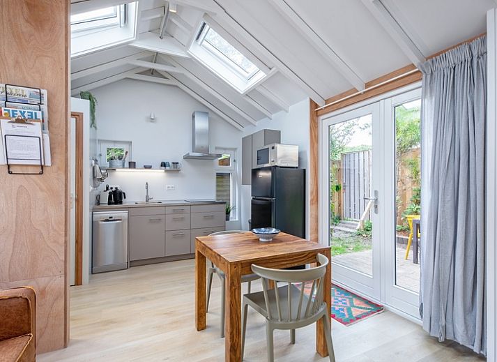 Gemuetlicher Innenbereich des Ferienhauses Pippa, De Koog, Texel, mit bequemem Sofa und Essecke.