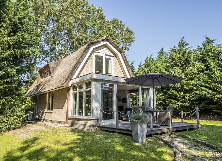 Vacation home Westenwind in De Koog, Texel with thatched roof and terrace among green trees.