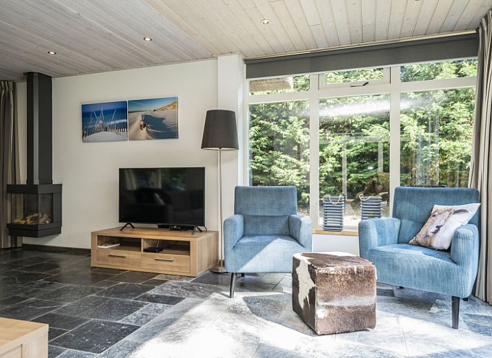 Bright living room of Westenwind vacation home in De Koog, Texel with comfortable seating area and view of the terrace.