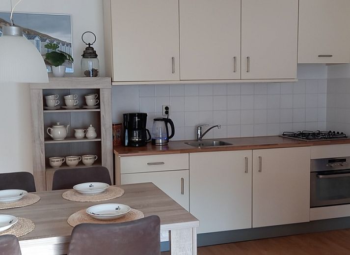 Eingang zu De Pelikaan Apartments, De Koog, Texel, umgeben von Gruenpflanzen und einem einladenden Eingang.