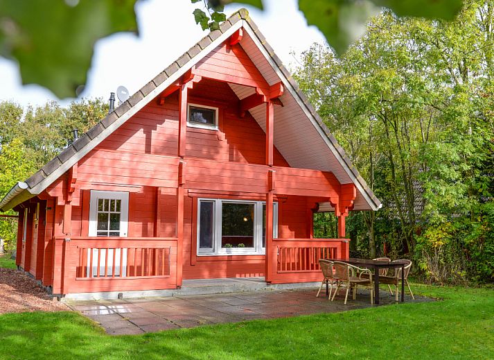 Charmantes Ferienhaus mit roter Fassade im Ferienpark Het Oude Dijkje, De Koog, Texel, umgeben von viel Gruen.