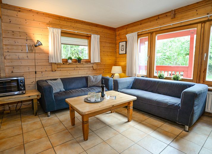 Charmantes Ferienhaus mit roter Fassade im Ferienpark Het Oude Dijkje, De Koog, Texel, umgeben von viel Gruen.