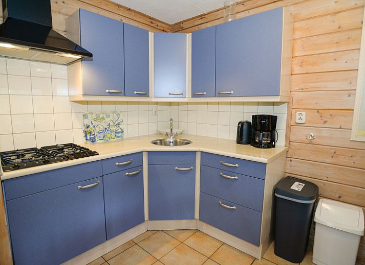 Charmantes Ferienhaus mit roter Fassade im Ferienpark Het Oude Dijkje, De Koog, Texel, umgeben von viel Gruen.