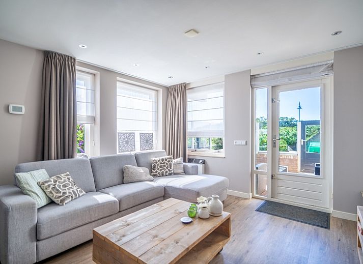 Cozy living room in Apartment Juliana 034 Eilandzicht, De Koog, Texel with comfortable sofa and garden view.