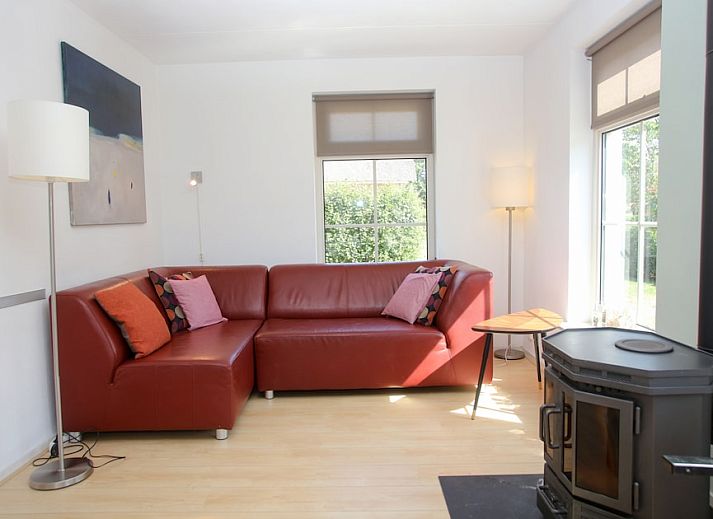 Bungalow T8A in De Koog, Texel met rieten dak en blauwe luiken, omgeven door groene natuur op de Waddeneilanden.