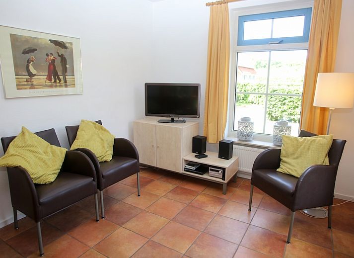 Bungalow T8A in De Koog, Texel met rieten dak en blauwe luiken, omgeven door groene natuur op de Waddeneilanden.