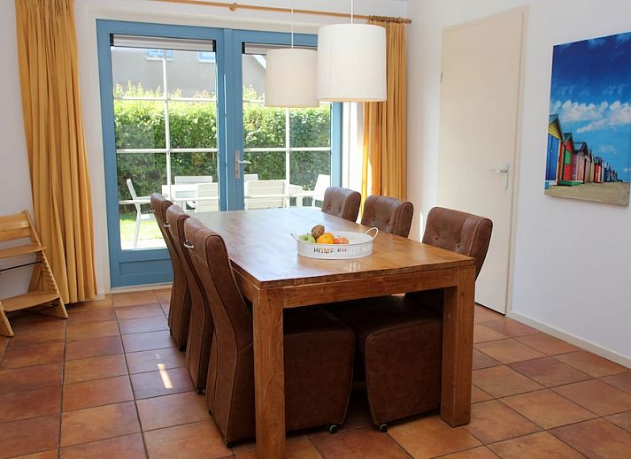 Bungalow T8A in De Koog, Texel met rieten dak en blauwe luiken, omgeven door groene natuur op de Waddeneilanden.