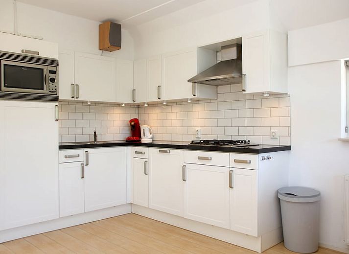 Bungalow T8A in De Koog, Texel met rieten dak en blauwe luiken, omgeven door groene natuur op de Waddeneilanden.