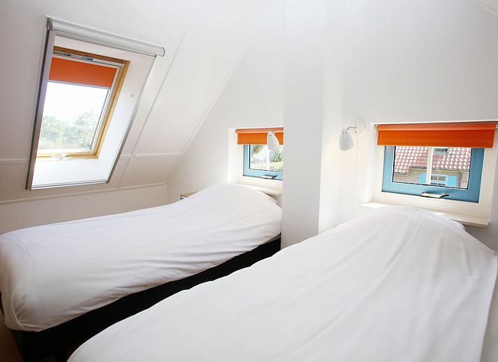 Gezellige woonkamer in bungalow T8A, De Koog, Texel met comfortabele rode bank en houtkachel, ideaal voor ontspanning op de Waddeneilanden.