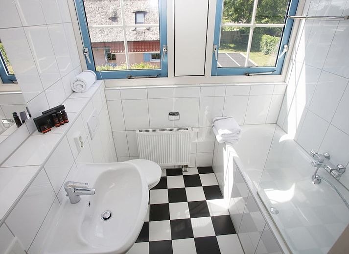 Gezellige woonkamer in bungalow T8A, De Koog, Texel met comfortabele rode bank en houtkachel, ideaal voor ontspanning op de Waddeneilanden.