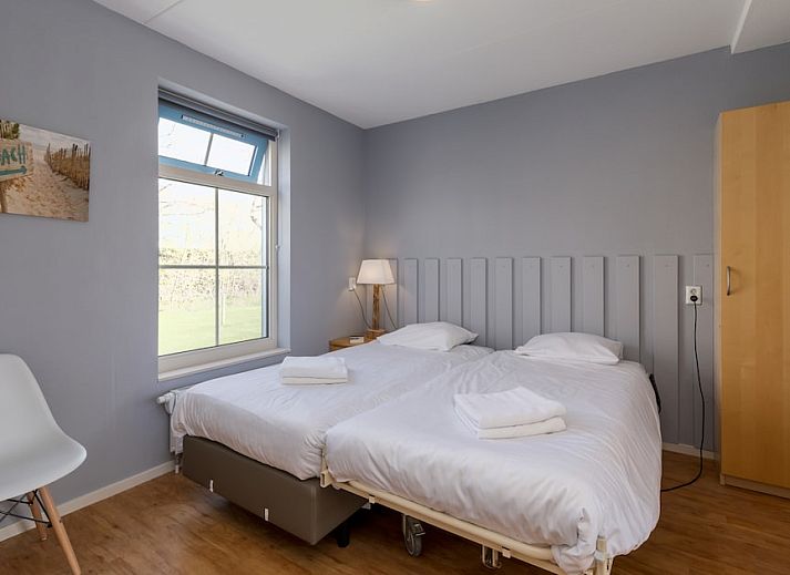 Helles Wohnzimmer des Bungalows T6AM in De Koog, Texel, mit komfortabler Einrichtung, Terrassentueren zur Terrasse und Gartenblick.