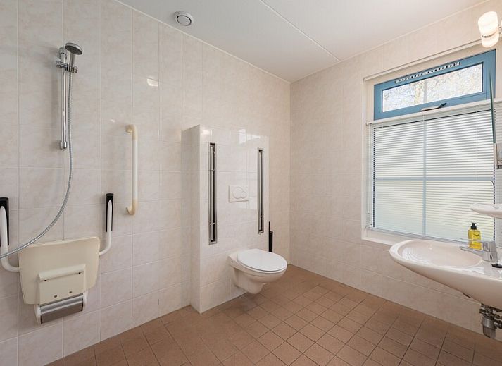 Helles Wohnzimmer des Bungalows T6AM in De Koog, Texel, mit komfortabler Einrichtung, Terrassentueren zur Terrasse und Gartenblick.