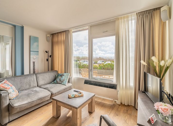 Gemuetliches Wohnzimmer des Appartements Juliana 076 Eilandzicht in De Koog, Texel mit Blick auf die Terrasse und viel Tageslicht.