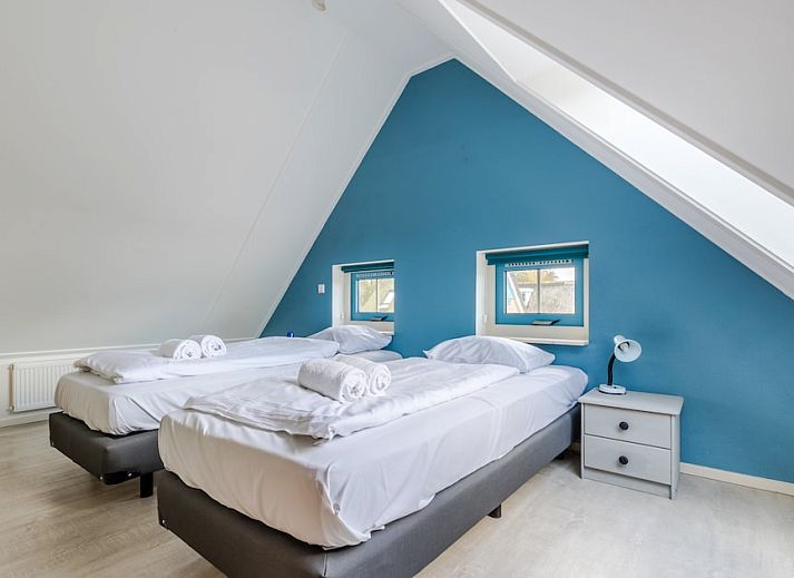 Charmante bungalow T6AB met rieten dak in De Koog, Texel, omringd door groene tuin en rustieke hek, ideaal voor een ontspannen vakantie op de Waddeneilanden.