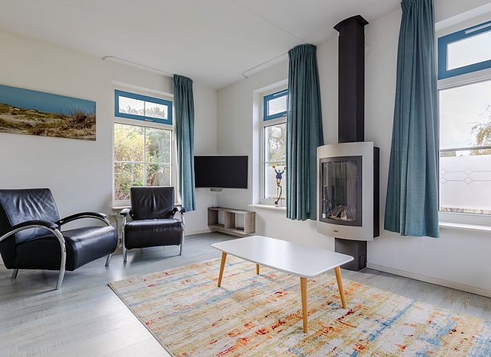 Charmante bungalow T6AB met rieten dak in De Koog, Texel, omringd door groene tuin en rustieke hek, ideaal voor een ontspannen vakantie op de Waddeneilanden.