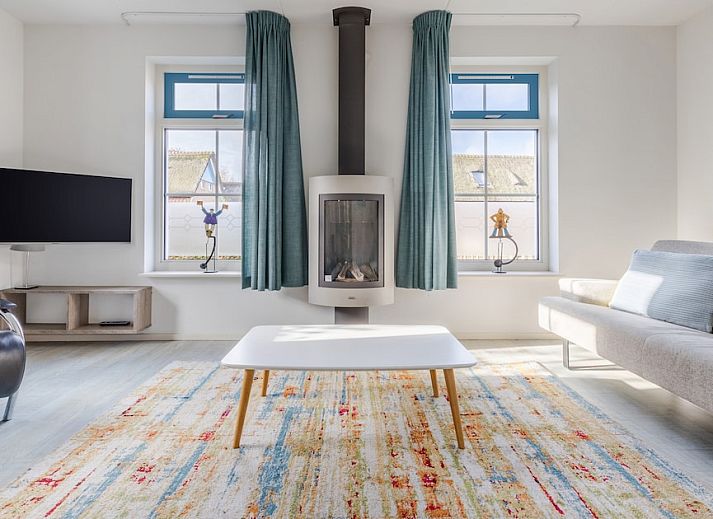 Charmante bungalow T6AB met rieten dak in De Koog, Texel, omringd door groene tuin en rustieke hek, ideaal voor een ontspannen vakantie op de Waddeneilanden.