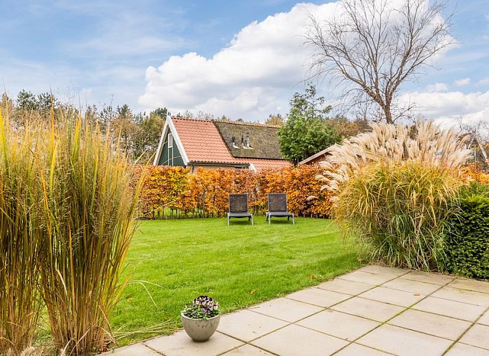 T6B Komfort-Bungalow in De Koog, Texel mit Reetdach und gemuetlicher Veranda, umgeben von Herbstfarben.