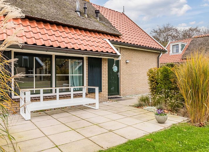 T6B Komfort-Bungalow in De Koog, Texel mit Reetdach und gemuetlicher Veranda, umgeben von Herbstfarben.