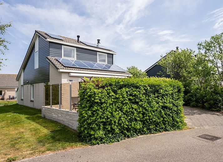 Ferienhaus Stappeland 169 in De Koog Texel mit gruenem Zaun und Sonnenkollektoren.