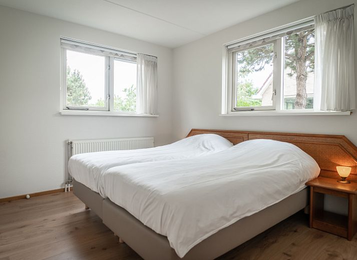 Spacious living room of Villa 304 in De Koog, Texel with comfortable seating area and garden view.