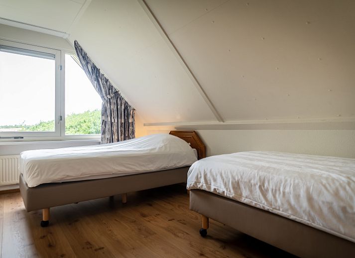 Spacious living room of Villa 304 in De Koog, Texel with comfortable seating area and garden view.