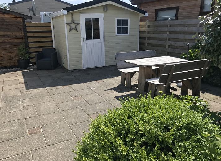 Vacation home Chalet Bregkoog 255 in De Koog, Texel with spacious garden and wooden fence, perfect for a relaxing vacation on the Wadden Islands.