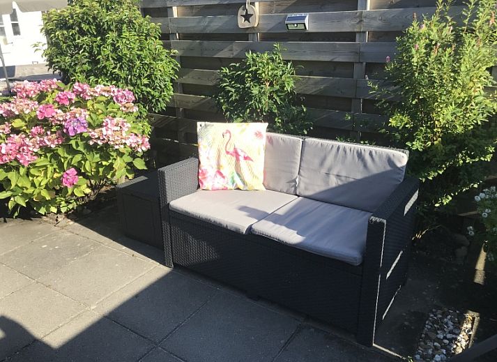Cozy living room of Chalet Bregkoog 255 in De Koog, Texel with comfortable sofa and lots of natural light, ideal for relaxation.