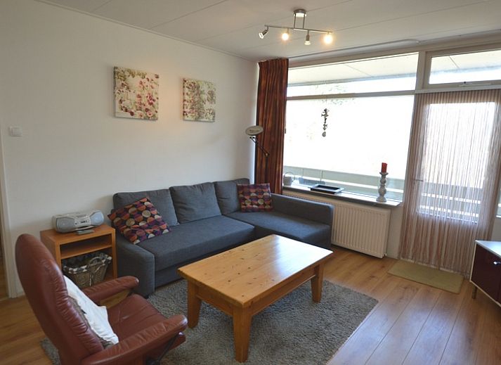 Cozy living room in Apartment Kerckeland 50, De Koog, Texel with comfortable seating area and bookshelves.