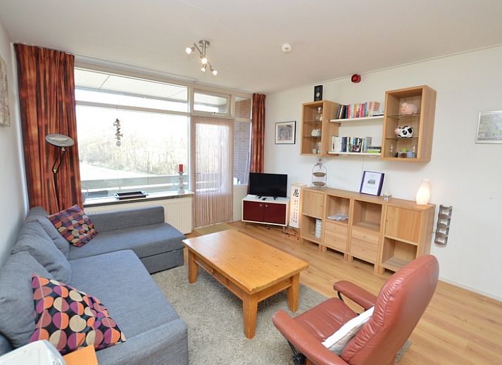 Cozy living room in Apartment Kerckeland 50, De Koog, Texel with comfortable seating area and bookshelves.