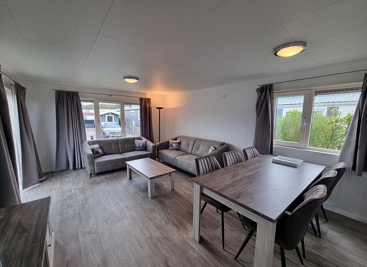 Cozy living room in Chaletpark Bregkoog - Chalet 240 De Texelse Berg, De Koog, Texel with comfortable sofas and dining area.