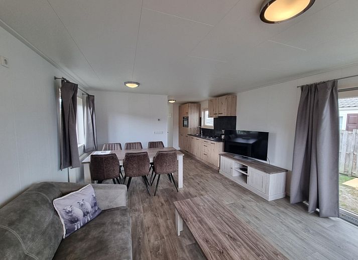 Cozy living room in Chaletpark Bregkoog - Chalet 240 De Texelse Berg, De Koog, Texel with comfortable sofas and dining area.