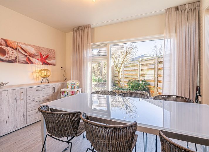 Gemuetliches Wohnzimmer in De Zandduyn, De Koog, Texel, mit rotem Sofa und grossen Fenstern fuer natuerliches Licht.