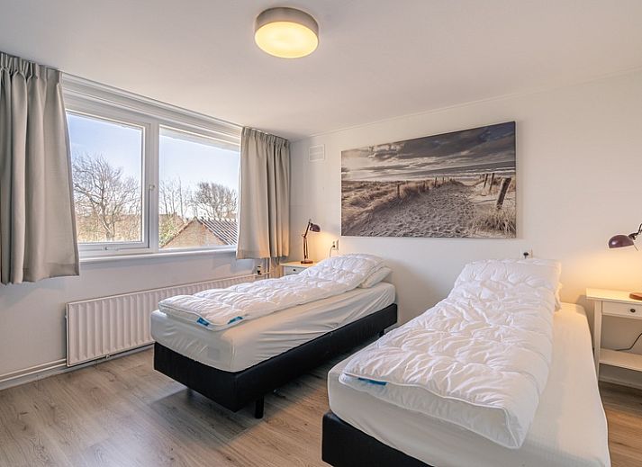 Gemuetliches Wohnzimmer in De Zandduyn, De Koog, Texel, mit rotem Sofa und grossen Fenstern fuer natuerliches Licht.