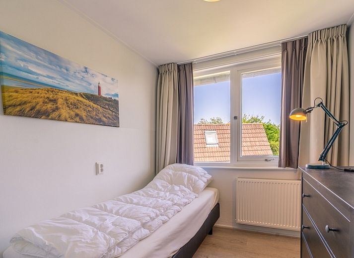 Gemuetliches Wohnzimmer in De Zandduyn, De Koog, Texel, mit rotem Sofa und grossen Fenstern fuer natuerliches Licht.