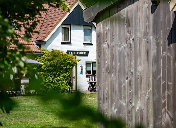 Landgoed Springtij - Koetshuis 2 in De Koog, Texel offers a charming vacation home with green surroundings and an inviting terrace.