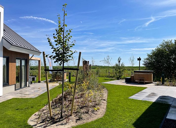 Bright living room in Duinvilla Wellness 6, Texel, with comfortable sofa and wooden wall decoration.