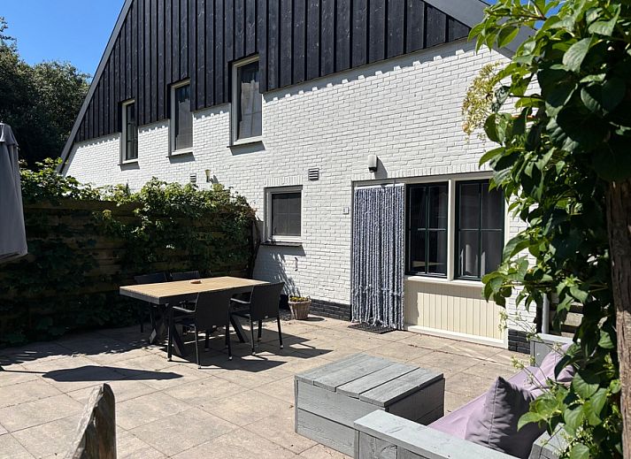 Spacious terrace at vacation home Stormvogel in De Koog, Texel with dining table and lounge sofa.