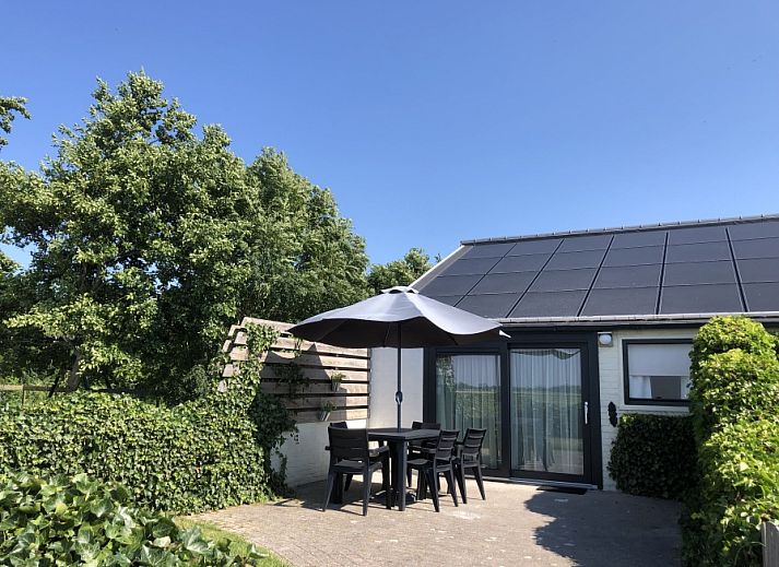 Spacious terrace at Bungalow 2 in De Koog, Texel with comfortable seating surrounded by green nature.