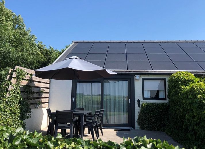Spacious terrace at Bungalow 2 in De Koog, Texel with comfortable seating surrounded by green nature.