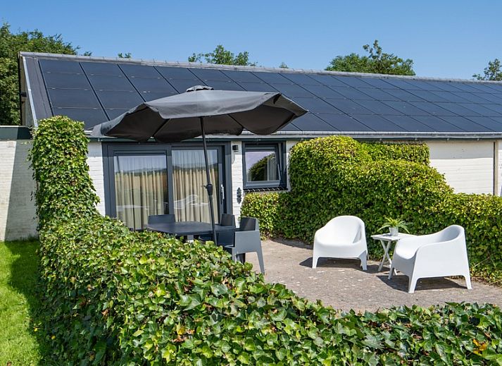 Spacious terrace at Bungalow 2 in De Koog, Texel with comfortable seating surrounded by green nature.