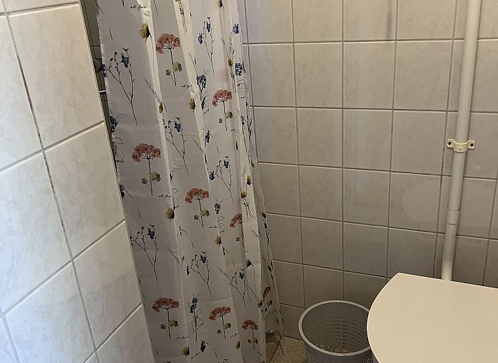 Terrace of Koetshuis 3 vacation home in De Koog, Texel with dining table and green planting.