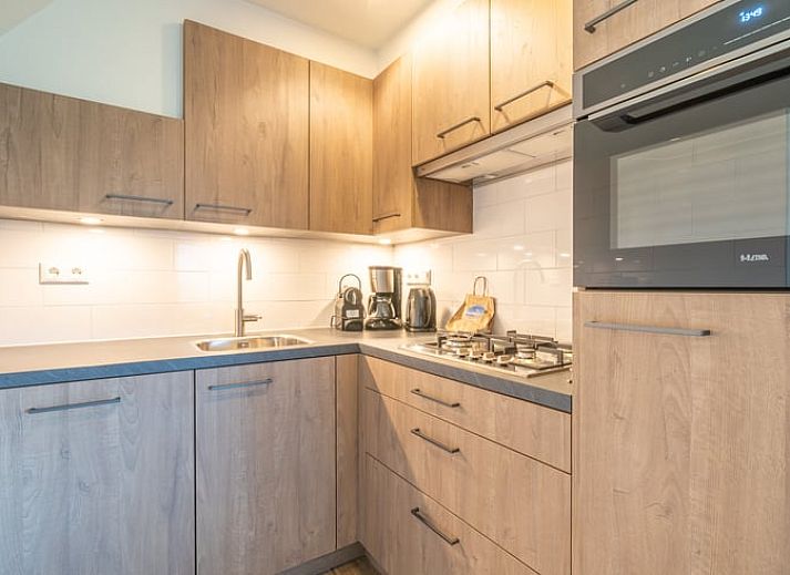 Gemuetliches Wohnzimmer im Ferienhaus in De Waal, Texel mit bequemem Sofa und moderner Einrichtung fuer einen entspannten Urlaub.