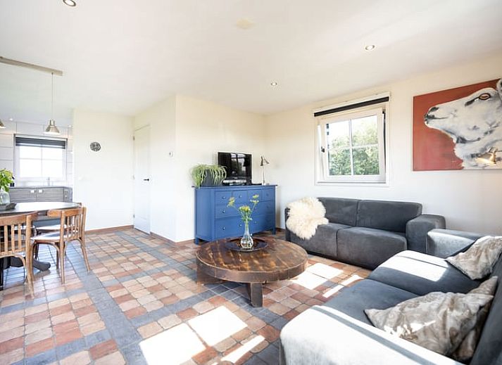 Ruime woonkamer van Huisje in De Waal, Texel, met veel lichtinval en toegang tot het terras.