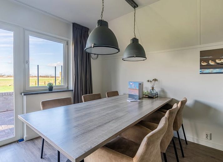Gemuetliches Wohnzimmer im Ferienhaus in De Waal, Texel mit bequemem Ecksofa und Blick auf die gruene Umgebung.