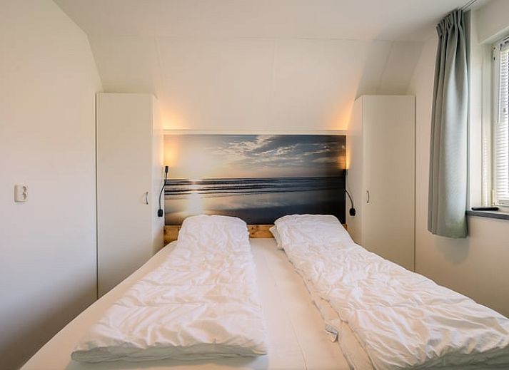 Gemuetliches Wohnzimmer im Ferienhaus in De Waal, Texel mit bequemem Ecksofa und Blick auf die gruene Umgebung.